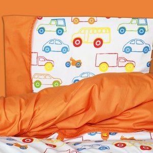 Könnte beinhalten: Orangenes Bettwäsche-Set mit Kissenbezug und Bettbezug. Der Kissenbezug zeigt bunte Illustrationen von Autos und Lastwagen auf weißem Hintergrund. Der Bettbezug ist einfarbig orange. Die Website www.giami-kids.de ist sichtbar.