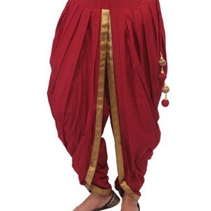 May include: Red dhoti trousers with gold trim and tassels. The trousers are pleated and have a drawstring waist.