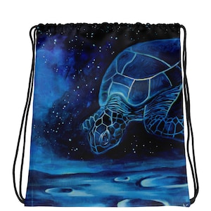 Può includere: Una borsa blu con coulisse con un dipinto di una tartaruga marina che nuota in un oceano blu scuro con uno sfondo di cielo stellato. La tartaruga ha riflessi blu chiaro. I cordini neri completano la borsa.