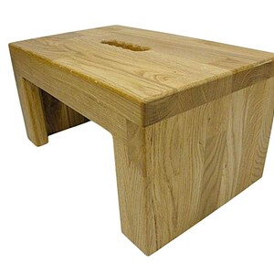 K&ouml;nnte beinhalten: Ein heller Holztritt mit rechteckiger Oberseite und Griff. Der Hocker hat ein schlichtes, modernes Design mit stabilem Fu&szlig; und ist aus Naturholz gefertigt. Der Hocker ist etwa 30 cm hoch.