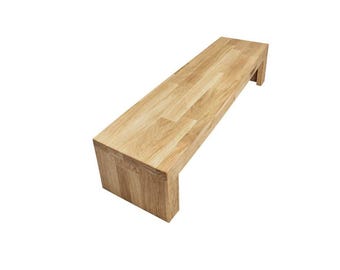 May include: A rectangular bench constructed from light-colored wood with a visible grain pattern. The bench features a flat top surface and two vertical side supports that extend to the floor, creating a clean, continuous, and solid structure.