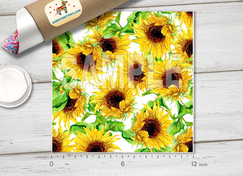 May include: A square print featuring a watercolor pattern of sunflowers with yellow petals and brown centers, interspersed with green leaves, against a white background. The word "SAMPLE" is overlaid on the design. The print measures approximately 12 inches.