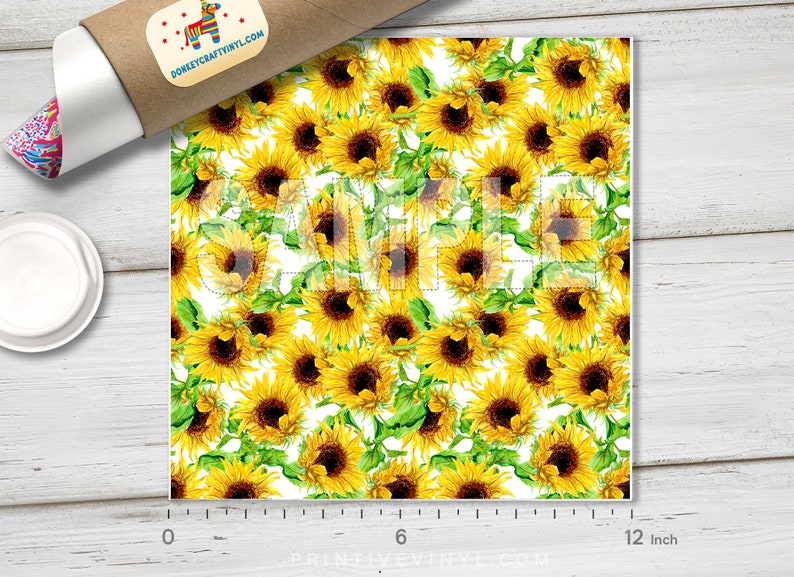 May include: A sheet of vinyl featuring a repeating pattern of yellow sunflowers with brown centers and green leaves on a white background. The sheet measures 12 inches wide. A roll of vinyl and a lid are in the image.