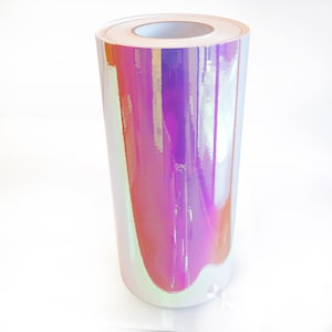 Puede incluir: Un rollo de pel&iacute;cula de vinilo iridiscente con un acabado hologr&aacute;fico. La pel&iacute;cula es de color morado claro con un brillo arco&iacute;ris.