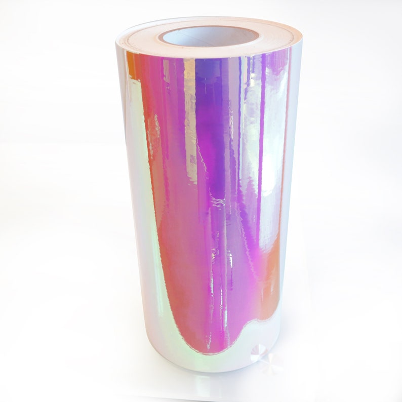 Puede incluir: Un rollo de pel&iacute;cula de vinilo iridiscente con un acabado hologr&aacute;fico. La pel&iacute;cula es de color morado claro con un brillo arco&iacute;ris.