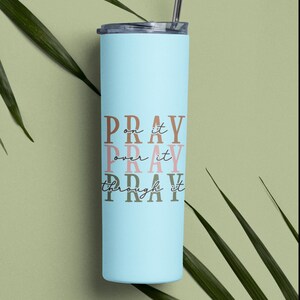 May include: A light blue stainless steel tumbler with a white lid and straw. The tumbler has the words "Pray on it, Pray over it, Pray through it" printed on it in brown, pink, and dark brown.