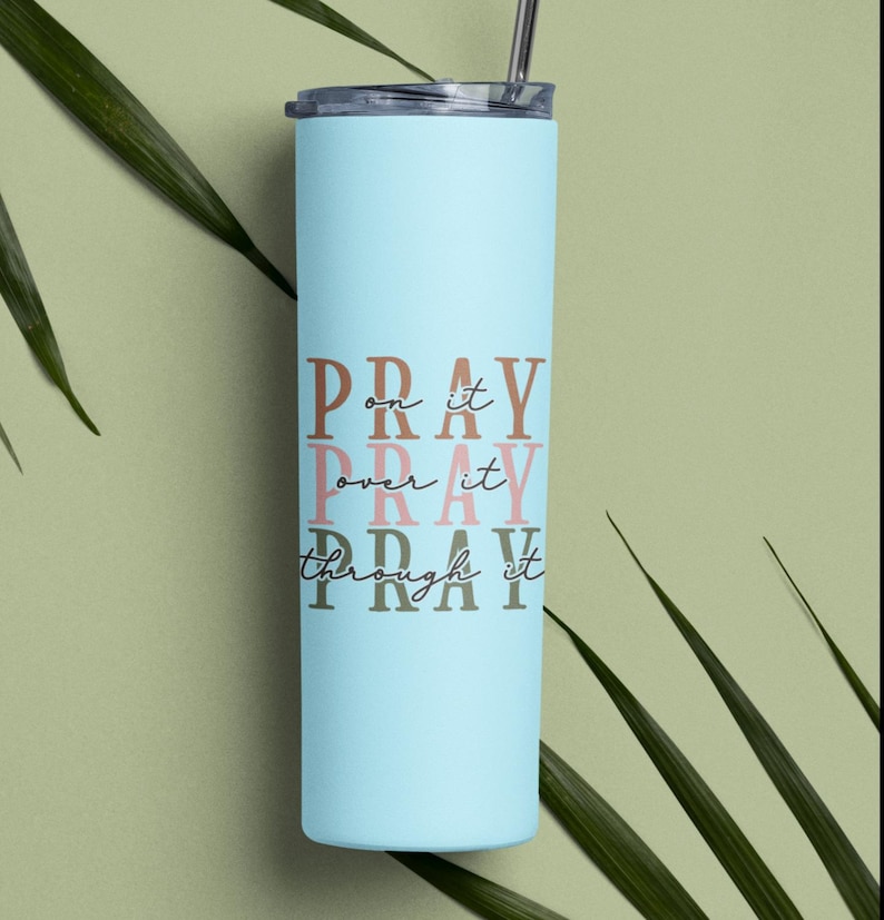 May include: A light blue stainless steel tumbler with a white lid and straw. The tumbler has the words "Pray on it, Pray over it, Pray through it" printed on it in brown, pink, and dark brown.