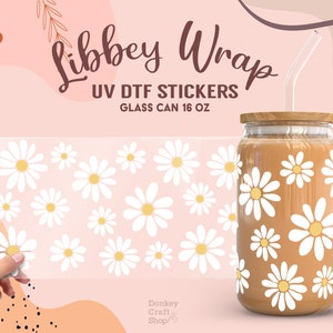 May include: A sheet of white daisy stickers for a 16 ounce glass can. The stickers are UV DTF and are shown on a glass can with a brown liquid inside. The text "Libbey Wrap UV DTF Stickers Glass Can 16 oz" is at the top of the image.