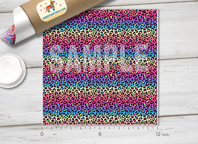 May include: A 12-inch by 12-inch sheet of rainbow leopard print vinyl. The vinyl has a black background with a rainbow pattern of pink, orange, yellow, green, blue, and purple leopard spots.