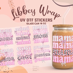 May include: A clear glass can-shaped tumbler with a wooden lid and a straw, featuring a pink and black "mama" design. The image also shows a sheet of UV DTF stickers with various family-related names like "mimi", "mom", and "gigi".