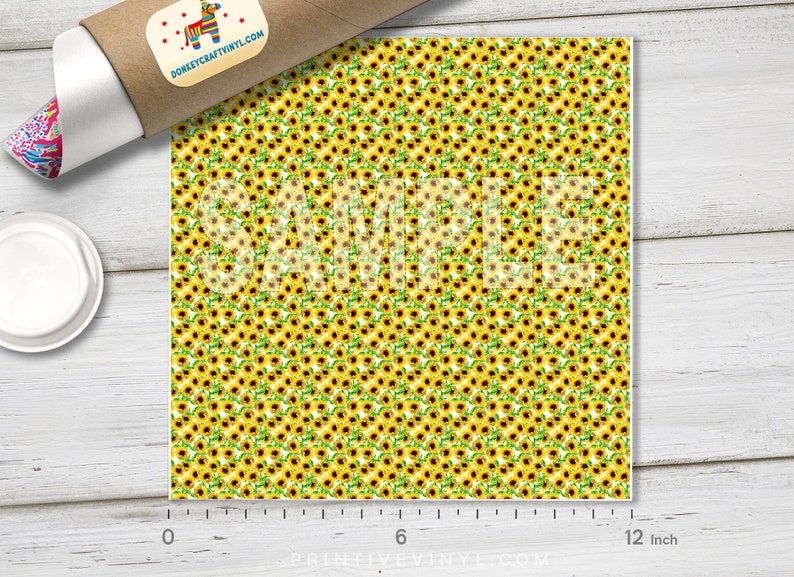 May include: A sheet of vinyl featuring a repeating pattern of yellow sunflowers with brown centers and green leaves. The word "SAMPLE" is printed across the design. The sheet is approximately 12 inches wide.
