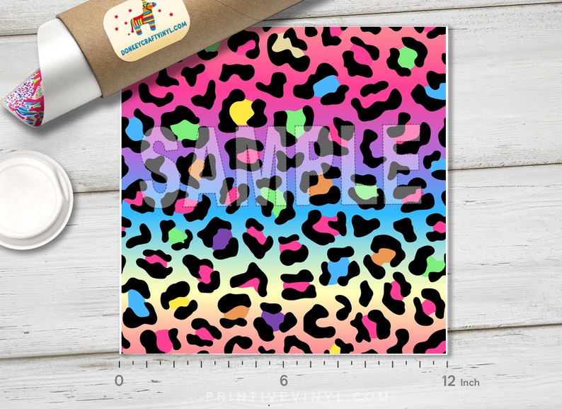 May include: A 12-inch square sheet of rainbow leopard print vinyl. The vinyl has a gradient of pink, orange, yellow, green, blue, and purple with black leopard spots.