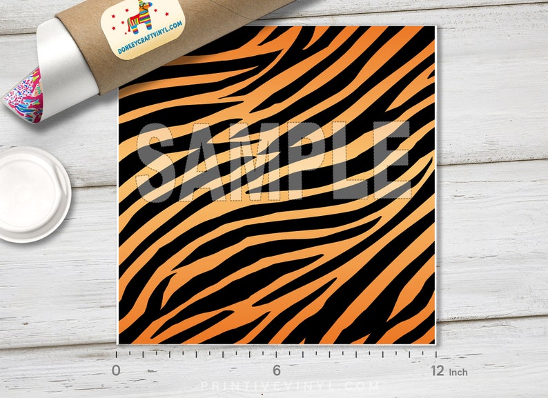 May include: A 12-inch square sheet of orange and black tiger stripe vinyl. The sheet is marked "SAMPLE" in white.