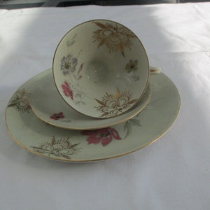 Peut inclure: Un service à thé vintage composé d'une tasse, d'une soucoupe et d'une assiette. Les pièces en porcelaine blanc cassé présentent des motifs floraux dorés, roses et gris. Les bords de la tasse et des assiettes sont dorés. Un service à thé classique.
