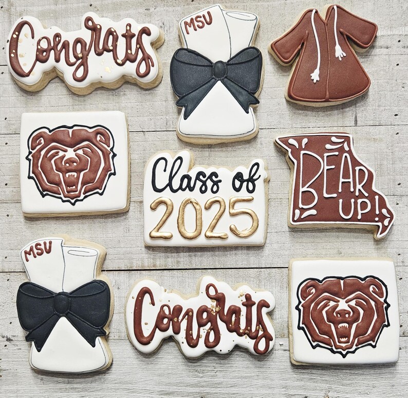 May include: A set of nine decorated sugar cookies with graduation themes. The cookies feature the words "Congrats", "Class of 2025", "Bear Up!" and a bear mascot. The cookies are decorated with brown, black, gold, and white icing.