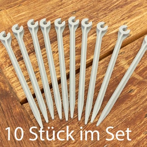 Könnte beinhalten: Zehn graue Plastik-Zeltheringe mit einem Haken an einem Ende. 10 Stück im Set.