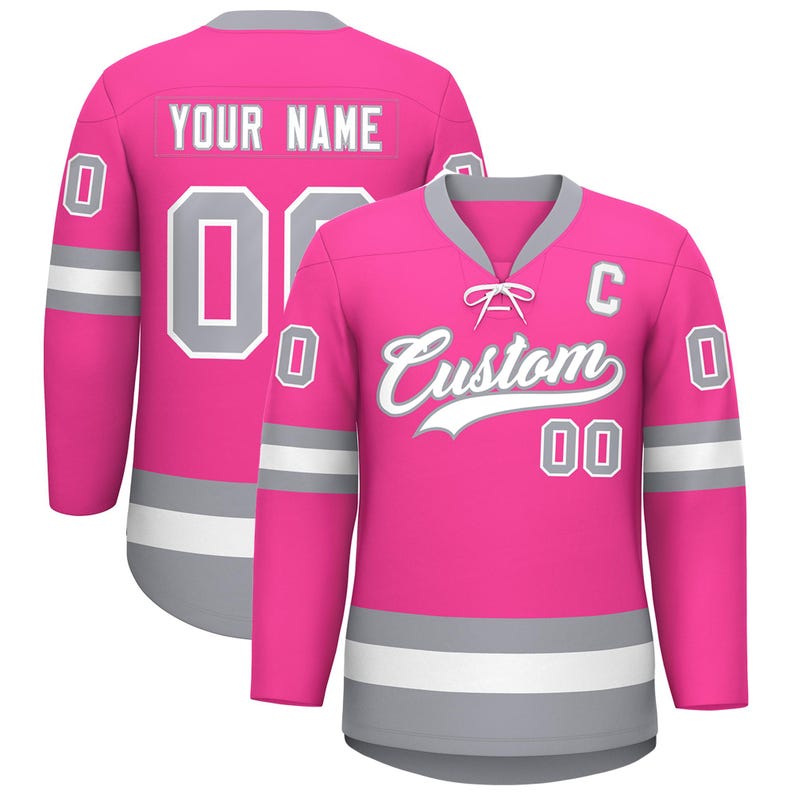 May include: A pink hockey jersey with the word "Custom" in white script on the front. The jersey has gray and white accents, with the number "00" in white on the front and back. The back of the jersey has the text "YOUR NAME" in white.