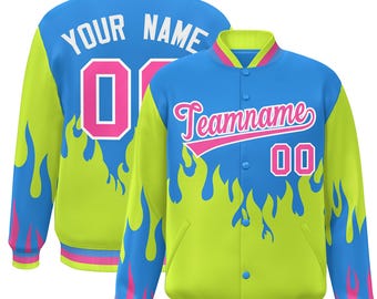 Puede incluir: Una chaqueta de béisbol verde y azul con un diseño de llamas. La chaqueta tiene un número rosa "00" en la parte delantera y el texto "Teamname" en la parte posterior. La chaqueta tiene una cremallera y botones decorativos.