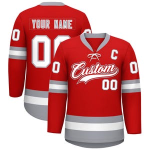 May include: Red custom hockey jersey with white and gray accents. The jersey features the word "Custom" in a stylized script, the number "00", and the text "YOUR NAME" on the back. The jersey has long sleeves and a gray collar.