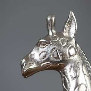 Puede incluir: Escultura de cabeza de jirafa de plata con detalles precisos y una superficie texturizada.