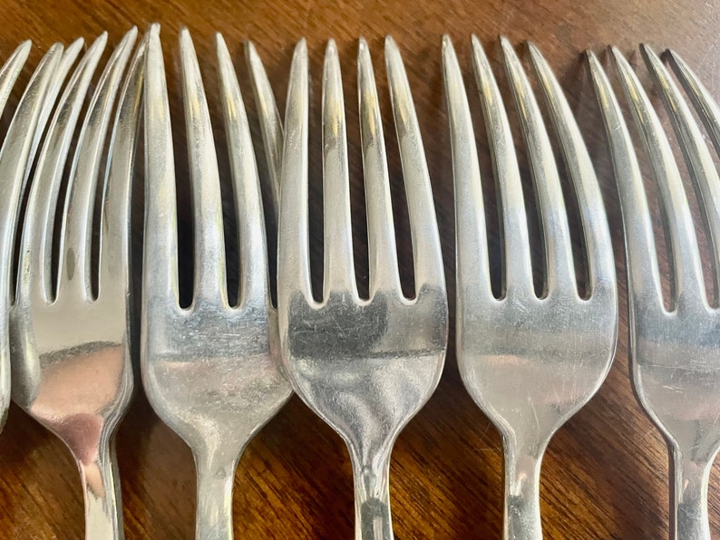 May include: Close-up of a set of six silver forks, showing the tines and polished surface.
