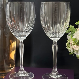 Pode incluir: Duas ta&ccedil;as de vinho de vidro transparente com um padr&atilde;o de nervuras verticais. As ta&ccedil;as t&ecirc;m um caule alto e fino e uma ta&ccedil;a larga.