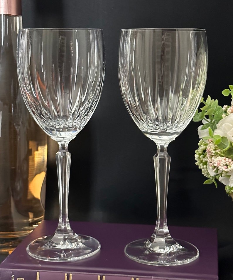 Pode incluir: Duas ta&ccedil;as de vinho de vidro transparente com um padr&atilde;o de nervuras verticais. As ta&ccedil;as t&ecirc;m um caule alto e fino e uma ta&ccedil;a larga.