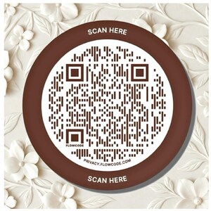 May include: A circular brown and white sign featuring a central QR code. The text SCAN HERE is printed at the top and bottom in white. The word FLOWCODE appears near the bottom left, and the URL PRIVACY.FLOWCODE.COM is printed at the bottom.