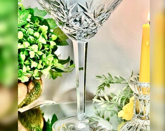 May include: A clear crystal martini glass featuring a faceted diamond and starburst cut pattern on the bowl, supported by a tall, smooth, multi-sided stem and a circular base. The glass is transparent with sharp, reflective edges.
