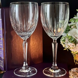 Pode incluir: Duas ta&ccedil;as de vinho de vidro transparente com um design de vidro cortado. As ta&ccedil;as est&atilde;o sobre uma superf&iacute;cie marrom.