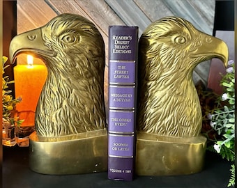 May include: A pair of brass eagle head bookends flanking a purple Reader's Digest Select Editions book. The book spine features the titles The Street Lawyer, Message in a Bottle, The Cobra Event, and Sooner or Later, with Volume 4 1998 at the base.