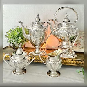 May include: A silver tea set with an ornate design. The set includes a teapot, creamer, sugar bowl, and a stand. The pieces are all highly polished and have a beautiful, intricate design.