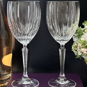 Pode incluir: Duas ta&ccedil;as de vinho de vidro transparente com um padr&atilde;o de nervuras verticais. As ta&ccedil;as est&atilde;o sobre uma superf&iacute;cie roxa.