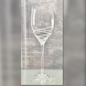 May include: A clear glass wine glass with a white etched design. The design is a series of intersecting lines.