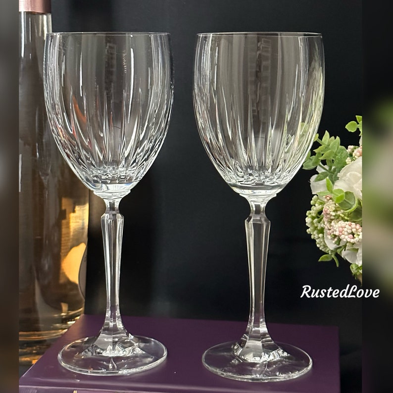 Pode incluir: Duas ta&ccedil;as de vinho de vidro transparente com um padr&atilde;o de nervuras verticais. As ta&ccedil;as t&ecirc;m um caule alto e fino e uma ta&ccedil;a redonda.