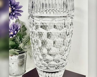 May include: A clear glass vase featuring a prominent hexagonal honeycomb pattern across its body, with a vertical ribbed design around the top rim and a smooth, flared base. The vase is cylindrical in shape with a thick, transparent glass construction.