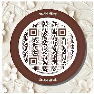 May include: A circular brown and white sign featuring a central QR code. The text SCAN HERE is printed at the top and bottom in white. The word FLOWCODE appears near the bottom left, and the URL PRIVACY.FLOWCODE.COM is printed at the bottom.