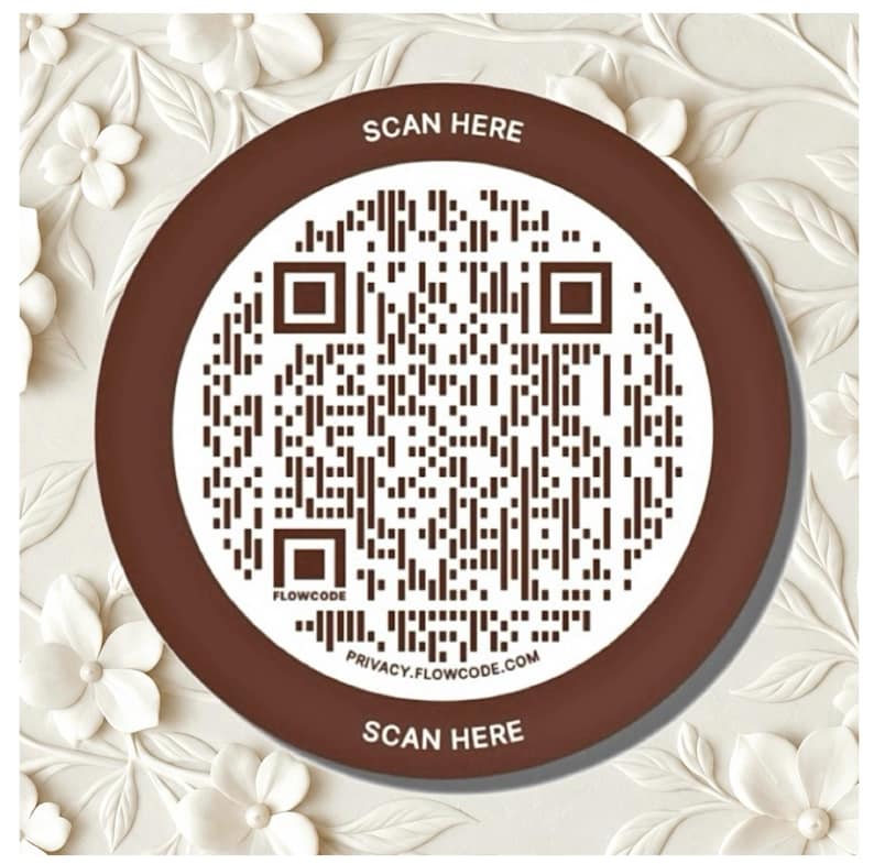 May include: A circular brown and white sign featuring a central QR code. The text SCAN HERE is printed at the top and bottom in white. The word FLOWCODE appears near the bottom left, and the URL PRIVACY.FLOWCODE.COM is printed at the bottom.
