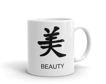May include: White ceramic mug featuring a black Chinese character and the word "BEAUTY" in a sans-serif font. The mug has a curved handle and a glossy finish, suitable for hot or cold beverages.