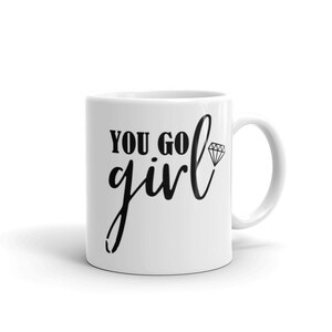 May include: White ceramic coffee mug with black text that reads "You go girl" and a small diamond graphic.