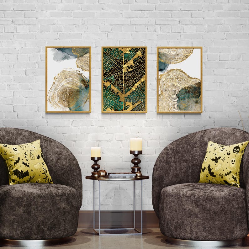 Puede incluir: Tres impresiones de arte abstracto enmarcadas con acentos dorados y verdes. Las impresiones est&aacute;n colgadas en una pared de ladrillo blanco sobre dos sillones de terciopelo marr&oacute;n con almohadas amarillas con un patr&oacute;n de Halloween.
