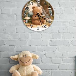 May include: A round wall clock featuring a brown bear sitting in a forest setting, reading a book surrounded by mushrooms and trees. The clock face displays black numbers from 1 to 12 and has black hour, minute, and second hands centred on the image.