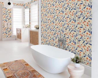 Könnte beinhalten: Ein Badezimmer mit einer freistehenden weißen Badewanne, einem gemusterten Teppich und floraler Tapete. Die Tapete hat einen cremefarbenen Hintergrund mit blauen Blättern und orangefarbenen Blumen. Der Raum hat weiße Böden und einen hölzernen Beistelltisch.