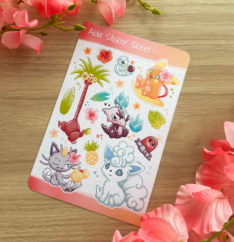 May include: A sticker sheet with a colourful tropical theme featuring various Pokemon characters from the Alola region. The sheet includes a palm tree, a surfing Vaporeon, a Rockruff, a Mimikyu, and a Rowlet. The text "Alola Sticker Sheet" is printed at the top of the sheet.