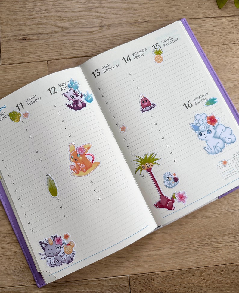 May include: A weekly planner with colourful stickers of cartoon characters. The stickers feature a variety of characters, including a pink and yellow character with a flower crown, a blue and white character with a flower crown, and a green character with a flower crown. The planner has a purple cover and is open to the week of June 11th to June 17th.