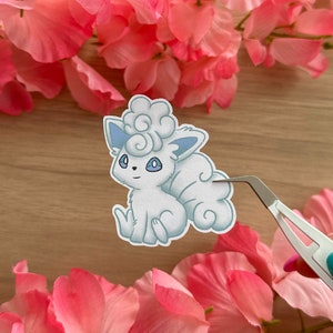 May include: A white and blue cartoon sticker of a fluffy, cloud-like Pokemon character with a curled tail.