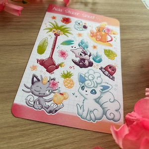 May include: A sticker sheet featuring various Pokemon characters from the Alola region, including a palm tree, a pineapple, and a cloud. The sticker sheet has a pink background with a grid pattern.