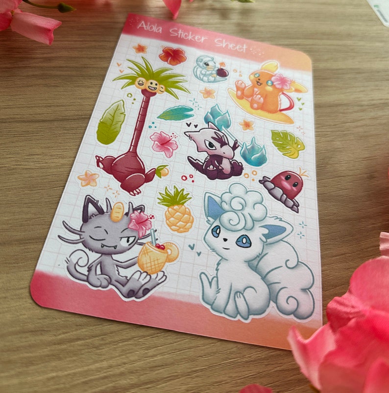 May include: A sticker sheet featuring various Pokemon characters from the Alola region, including a palm tree, a pineapple, and a cloud. The sticker sheet has a pink background with a grid pattern.