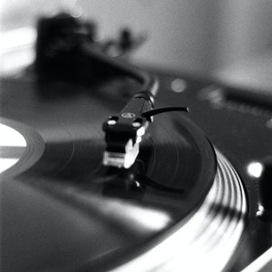 May include: A black and silver record player with a vinyl record on the turntable. The needle is resting on the record, and the record is spinning.