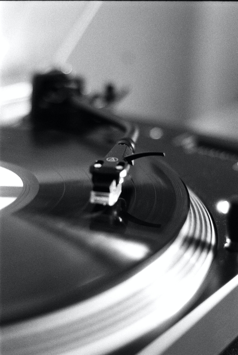 May include: A black and silver record player with a vinyl record on the turntable. The needle is resting on the record, and the record is spinning.